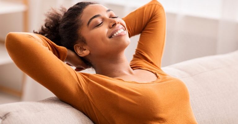 smiling-young-woman-on-couch-leans-back-768